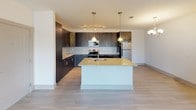 Located at 12769 Persimmon Tree Dr in Charlotte, NC, this single-floor residence offers a well-designed layout that balances modern finishes with comfortable living. The kitchen serves as a striking centerpiece, showcasing dark espresso cabinetry that extends floor to ceiling, granite countertops, a white subway tile backsplash, and a large central island with pendant lighting overhead. Stainless steel appliances, including a range, microwave, and refrigerator, complete this functional and stylish space. Light wood-style flooring runs throughout the kitchen and living areas, adding warmth and continuity.

The living area is generously proportioned, bathed in natural light through multiple windows fitted with blinds, and features a ceiling fan with a decorative light fixture. A door provides direct exterior access, enhancing the open, airy feel of the space.

The bedrooms are carpeted for comfort and each include ceiling fans, ample natural light, and access to additional rooms or closet space. The neutral color palette throughout keeps the atmosphere clean and inviting.

The bathroom is bright and well-appointed, featuring a soaking tub with a tiled surround, granite-topped vanity, and brushed nickel fixtures. A convenient stacked washer and dryer unit is integrated into the bathroom area, offering practical in-unit laundry access.