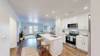 Located at 1 Woodlake Blvd, Unit 109 in Gurnee, IL, this well-appointed 1-bedroom, 1-bathroom residence offers a thoughtfully designed single-floor layout. The open-concept living and kitchen area serves as the heart of the home, where warm hardwood-style flooring, recessed lighting, and a bright, airy color palette create a welcoming atmosphere. The kitchen is a standout feature, boasting crisp white shaker cabinetry extending to the ceiling, quartz countertops, a subway tile backsplash, and a full suite of stainless steel appliances including a refrigerator, electric range, and built-in microwave. A central island with a built-in sink and seating provides additional prep and dining space. The living room is bathed in natural light from a set of glass doors that open to a private outdoor area, offering pleasant outdoor views. The spacious bedroom features plush carpeting, a wide window with blinds, and generous closet access. The bathroom is finished with classic black-and-white mosaic tile flooring, a full tub-shower combination, and clean white fixtures. A dedicated hallway and closet provide practical storage throughout the unit.