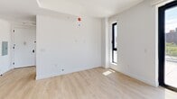 Located in East Harlem at 205 E 110th Street, this contemporary 2-bedroom, 2-bathroom residence offers a thoughtfully designed layout with modern finishes throughout. Light-toned hardwood floors run continuously through the living areas and bedrooms, lending a warm, cohesive feel to the space.

The kitchen is a standout feature, outfitted with sleek white and natural wood cabinetry extending to the ceiling, a stainless steel range, integrated appliances, a black matte faucet, and white quartz countertops. A large window frames open city views, filling the kitchen with natural light.

The primary bedroom is generously sized and opens directly onto a wide outdoor terrace through full-height glass doors, offering panoramic views of the Manhattan skyline and surrounding East Harlem neighborhood. The second bedroom also benefits from abundant natural light through large black-framed windows with terrace access.

The bathrooms are elegantly finished with floor-to-ceiling marble-look tile, a glass-enclosed shower, a wood-toned vanity with black fixtures, and a mirrored medicine cabinet — combining clean modern design with refined materials.

The expansive private terrace, accessible from multiple rooms, is tiled in large-format stone pavers and enclosed by a sleek glass railing, offering an exceptional outdoor retreat above the city.
