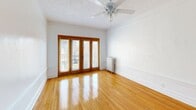 Located at 6930-6942 S Crandon Ave in Chicago's South Side, this well-appointed one-bedroom, one-bathroom unit offers a thoughtfully laid-out single-floor plan. Warm-toned hardwood floors run throughout the living spaces, reflecting natural light and lending a classic character to every room. The living room is a standout area, featuring a striking wood-paneled accent wall, crown molding, and a set of full-length French doors that invite abundant natural light and connect to the exterior. A ceiling fan adds comfort, while a traditional cast-iron radiator provides reliable heating. The dining room flows naturally from the living area, maintaining the same rich hardwood flooring and clean white walls. The bedroom is comfortably sized, complete with a ceiling fan, radiator, and a built-in closet. The unit offers three closets in total, providing ample storage throughout. The kitchen is equipped with a gas range, refrigerator, white cabinetry with a tile backsplash, and a window for natural ventilation, along with a separate exterior door. The bathroom features a tiled tub-surround with a marble-like finish, a combined tub and shower, and a frosted privacy window. Two hallways connect the rooms efficiently, completing this classic Chicago-style residence.