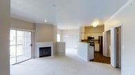 Located at 6805 West Bowles Avenue in Littleton, Colorado, this single-floor residence offers a thoughtfully designed open-concept layout that seamlessly connects the living, dining, and kitchen areas. The living room is anchored by a classic fireplace with a clean white mantle, providing a warm focal point for the space. Plush carpeting throughout the living and dining areas adds comfort underfoot, while durable hardwood-style flooring defines the kitchen zone. A sliding glass door invites natural light and provides convenient access to the outdoors. The kitchen is well-appointed with white cabinetry, stainless steel appliances including a range, microwave, and refrigerator, and a peninsula with bar-height seating that doubles as a casual dining area. A pendant light fixture above the peninsula adds a subtle design touch. The textured ceiling and neutral warm-toned walls create a calm, inviting ambiance throughout. A hallway leads to the additional rooms of the home, offering a practical and efficient floor plan. This residence combines functional design with comfortable finishes, making it a welcoming space in the Littleton community.