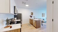 Located at 821 East Main Street in Stamford, Connecticut, this well-designed one-bedroom, one-bathroom residence offers a thoughtfully efficient layout with modern finishes throughout. Light hardwood flooring flows seamlessly across the entire living space, complementing the crisp white walls and creating a bright, cohesive aesthetic.

The open-concept kitchen is equipped with stainless steel appliances, including a refrigerator, range, and over-the-range microwave. White upper cabinetry pairs with warm wood-toned lower cabinets, accented by a subway tile backsplash and quartz countertops. A peninsula with seating provides additional prep and dining space, while a stainless steel sink with a matte black faucet adds a contemporary touch.

The living room is generously sized, filled with natural light from large windows and a glass door that opens to a private balcony overlooking the Stamford skyline. The spacious primary bedroom features a large window with urban views and an open closet area, offering practical storage. The bathroom is finished with a wood-toned vanity, white quartz countertop, a rectangular mirror with a sleek black frame, and matte black fixtures throughout, rounding out the modern design of this Stamford residence.