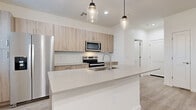 Located at 7850 S Central Ave in Phoenix, AZ, this two-story home offers six bedrooms and three bathrooms across two well-organized floors. The main level houses the living room, kitchen, garage, and laundry room, while the more expansive upper floor accommodates the majority of the bedrooms and bathrooms. Throughout the home, light wood-look flooring and a clean, neutral color palette create a bright and cohesive modern aesthetic.

The kitchen is a standout feature, centered around a large white quartz island with an undermount sink and stylish pendant lighting. Light-toned wood cabinetry lines the walls alongside a full suite of stainless steel appliances, including a refrigerator, electric range, and built-in microwave. The living area is open and airy, with ceiling fans and recessed lighting providing comfort and functionality.

The six bedrooms are well-proportioned, each finished with the same light flooring and ceiling fans. The primary bedroom offers generous space, while a dedicated closet with built-in shelving and hanging rods provides organized storage. Bathrooms are clean and modern, featuring pedestal sinks with brushed nickel fixtures. A dedicated laundry room includes a full-size washer and dryer. The attached garage is spacious, with an automatic opener and a polished concrete floor, completing this highly functional home.