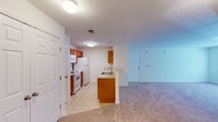 This single-floor residence at 2206 Juliet Place in Greensboro, North Carolina, offers a practical and well-organized layout with a clean, neutral aesthetic throughout. The open-concept living area is generously proportioned, featuring wall-to-wall carpeting, crisp white walls, and a large window that allows natural light to fill the space and offers views of surrounding greenery. A separate entry door opens directly into this living area, which flows seamlessly toward the kitchen.

The galley-style kitchen is efficiently designed, featuring warm medium-toned wood cabinetry lining both sides of the room, light-colored countertops, and tile flooring. White appliances include an electric range, over-the-range microwave, and refrigerator. A peninsula with a sink and additional cabinetry below separates the kitchen from the living space, providing a convenient transition between the two areas.

The bedrooms are carpeted and well-sized, each featuring windows with blinds that bring in natural light and outdoor views. One bedroom includes a ceiling fan with a light fixture. The bathroom features a full-sized soaking tub with an overhead shower and a grab bar, finished in clean white surroundings. Double closet doors in the living area provide ample storage space throughout the unit.