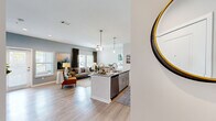 Located at 8207 NW Selvitz Rd in Port Saint Lucie, Florida, this single-story home offers three bedrooms and two bathrooms within a thoughtfully designed open-concept floor plan. Light-toned hardwood-style flooring flows consistently throughout, enhancing the cohesive and airy feel of the space.

The kitchen and living area form the heart of the home, where a granite-topped island with bar seating serves as a central gathering point. Gray shaker-style cabinetry, stainless steel appliances, a subway tile backsplash, and pendant lighting complete the kitchen. An in-unit washer and dryer with dedicated shelving is conveniently located adjacent to the kitchen. The living room receives abundant natural light through multiple windows and a glass door, complemented by a ceiling fan overhead.

The primary bedroom features a walk-in closet outfitted with multi-level shelving and hanging rods. Both bathrooms include granite-topped vanities with gray cabinetry; one bathroom features a tub-shower combination with white tile surround. The remaining bedrooms offer comfortable proportions with the same consistent flooring found throughout the home. Soft, neutral wall tones create a calm and welcoming ambiance across all rooms.