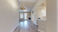 Located at 198 Mill Bayou Blvd in Lynn Haven, FL, this two-story home offers a well-designed layout spread across two floors. The ground floor houses an attached garage with an automatic opener and a utility room, providing ample storage and functional space. Stairs lead up to the main living level, where an open-concept kitchen and living room create a bright, inviting atmosphere. The living room features warm wood-look flooring, vaulted ceilings, a elegant chandelier, and a corner electric fireplace with a clean white mantle. A sliding glass door opens onto a private balcony with open neighborhood views. The kitchen is outfitted with white shaker cabinetry, white countertops, stainless steel appliances including a range, microwave, dishwasher, and refrigerator, plus a stylish sliding barn door and light wood-look flooring. The spacious primary bedroom includes its own closet, while the second bedroom features plush carpeting, a ceiling fan, and natural light from a window. A full bathroom with a tub/shower combination serves both bedrooms. Two closets and a hallway round out the upper floor, offering practical storage throughout this thoughtfully laid-out Lynn Haven home.