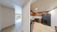 Located at 1981 NW 43rd Terr, Unit 460, in Lauderhill, Florida, this one-bedroom, one-bathroom residence offers a well-organized, single-floor layout designed for comfortable everyday living. Gleaming large-format ceramic tile flooring runs throughout the entire unit, lending a clean, cohesive look to every room.

The open living and dining area is bathed in natural light, anchored by sliding glass doors that lead to a private balcony with outdoor views of surrounding greenery. The kitchen is efficiently designed with warm wood cabinetry, light stone countertops, a classic subway tile backsplash, and black appliances including a refrigerator, dishwasher, and range. A drop ceiling with recessed lighting adds a finished touch to the kitchen space.

Two hallways connect the living areas to the private quarters, providing a sense of separation and privacy. The spacious primary bedroom features a large window dressed with vertical blinds, filling the room with natural light. Three closets throughout the unit offer generous storage. The bathroom includes a full tub-shower combination with clean white tile surrounds.

The unit's neutral color palette, abundant natural light, and practical layout make it a well-rounded residential space in South Florida.