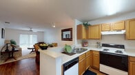 This single-floor residence offers a thoughtfully designed open-concept layout that seamlessly connects the kitchen, dining, and living areas. The kitchen is equipped with warm honey-toned cabinetry, white countertops, a built-in dishwasher, electric range, and a peninsula that doubles as a breakfast bar — ideal for both everyday cooking and casual dining. Adjacent to the kitchen, the dining area features hardwood-style flooring and is accented by a decorative mirror, creating an inviting space for meals. The living room is generously proportioned, filled with natural light from a large sliding glass door that opens to an outdoor view. A ceiling fan adds to the comfort of this relaxed gathering space, which is finished with soft carpet underfoot. The two bedrooms are serene and well-sized, each featuring plush carpeting, ample closet storage, and large windows dressed with vertical blinds that allow for adjustable natural light. The full bathroom is clean and functional, offering a wide vanity with a granite-style countertop, a large mirror, hardwood-style flooring, and a tub-shower combination. Throughout the residence, a neutral color palette and consistent finishes create a cohesive, comfortable ambiance.