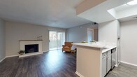 This single-floor, 1-bedroom, 1-bathroom residence offers a thoughtfully designed layout that balances comfort and functionality. Throughout the unit, dark hardwood-style flooring provides a cohesive and contemporary feel, complemented by neutral gray walls and textured ceilings.

The open living area serves as the heart of the home, highlighted by a classic fireplace with a clean white mantel and large sliding glass doors that lead to a private balcony, allowing natural light to flow freely into the space. The kitchen is efficiently arranged in a galley style, featuring stainless steel appliances — including a refrigerator, range, and dishwasher — paired with gray cabinetry, light countertops, and a skylight that brightens the workspace. A peninsula counter seamlessly connects the kitchen to a dedicated dining area, which is accented by a chandelier overhead.

The bedroom is generously sized and includes a ceiling fan with light, vertical blinds on the sliding glass doors, and a side window for additional natural light. The bathroom offers a clean, functional design with a full tub-shower combination, wood-style flooring, and a vanity with light countertops. This unit presents a practical and comfortable living space with well-maintained finishes throughout.