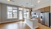 Located at 4429 NC-55 E in Cary, NC, this contemporary single-floor residence offers a thoughtfully designed open-concept layout with modern finishes throughout. The kitchen serves as the heart of the home, showcasing a large central island topped with granite countertops, a undermount sink, and stylish pendant lighting. Rich wood-toned cabinetry extends to the ceiling for ample storage, while a full suite of stainless steel appliances — including a refrigerator with ice maker, electric range, and built-in microwave — completes the space. Large windows and a glass door flood the kitchen and living area with natural light, offering views of the surrounding neighborhood. Warm hardwood-style flooring flows seamlessly through the main living areas, complemented by neutral-toned walls and clean white trim. The primary bathroom features a dual-sink granite vanity with warm wood cabinetry, a large mirror, and a separate shower. A secondary bathroom provides a tub-shower combo with a single granite vanity. The carpeted bedrooms offer a comfortable retreat, with generous closet space including a walk-in closet with wire shelving. A ceiling fan in the living area and recessed lighting throughout add functional elegance to this well-appointed Cary residence.