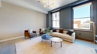 Located on Euclid Avenue in the heart of Cleveland, this thoughtfully designed one-bedroom, one-bathroom residence offers a well-appointed urban living experience. The open-concept kitchen and living area serves as the centerpiece of the home, where a sleek kitchen showcases white cabinetry, dark quartz countertops, stainless steel appliances, a textured tile backsplash, and a large central island with pendant lighting and bar seating — ideal for both cooking and entertaining. The living room is bathed in natural light through oversized windows framing city views, and features a refined palette of warm neutrals and deep slate tones, complemented by a striking multi-arm brass chandelier. The bedroom continues the clean, contemporary aesthetic with large windows offering urban views, soft gray walls, and warm wood accents. The bathroom is finished with crisp white walls, bold black fixtures, a glass-enclosed walk-in shower, and a distinctive star-patterned tile floor that adds a touch of character. Light-toned flooring runs throughout, unifying the space with a cohesive, modern feel. A hallway connects all rooms efficiently, completing this polished and practical urban residence.
