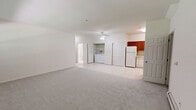 Located at 1100 Lake Drive in Medford, NY, this single-floor unit offers a practical and well-organized layout with two bedrooms, two bathrooms, and a combined kitchen and living area. The entry foyer features tile flooring and an arched transom window above the front door, creating a welcoming first impression. The living room is bright and open, with soft carpet, baseboard heating, and a window that fills the space with natural light. The kitchen is fully equipped with rich wood cabinetry, ample counter space, tile flooring, and white appliances including a refrigerator, range, microwave, and dishwasher — offering generous storage and workspace. Both bedrooms are carpeted and fitted with ceiling fans, wall-unit air conditioning, and baseboard heating for year-round comfort. The generously sized primary bedroom includes a walk-in closet and multiple windows with views of surrounding greenery. The second bedroom also offers outdoor views through its window. The two bathrooms are finished with white tile flooring and vanities; one features a glass-enclosed shower stall, while the other includes a bright vanity with a mirrored medicine cabinet. Two additional closets provide practical storage throughout the unit.