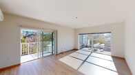 This modern single-floor unit is designed with a clean, contemporary aesthetic throughout. Light-toned hardwood flooring runs continuously across the space, complementing the crisp white walls and warm wood-trimmed baseboards and doors that provide a cohesive visual accent.

The open living area is bathed in natural light, courtesy of expansive floor-to-ceiling sliding glass doors that lead to a private balcony. The balcony offers pleasant views of surrounding greenery and the urban streetscape beyond. A wall-mounted mini-split system ensures year-round climate comfort in this space.

The kitchen is efficiently designed in a galley layout, featuring granite countertops with subtle veining, a stainless steel sink, and a full suite of stainless steel appliances including a refrigerator, dishwasher, electric range, and built-in microwave. White cabinetry extends from countertop to ceiling, providing generous storage.

The bedroom is a calm, sun-filled retreat with a large window framing views of the neighborhood. Warm-toned hardwood flooring and a set of sliding wood panel closet doors add both function and style to the room.

The overall ambiance of the unit is clean, light, and modern, with thoughtful finishes that balance practicality with contemporary urban living.