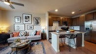 This single-floor residence is designed with an open-concept layout that seamlessly connects the living area and kitchen, creating a cohesive and functional living environment. Wood-style flooring runs throughout, providing a consistent, warm foundation that unifies the space.

The living area is bright and inviting, anchored by recessed lighting and a gallery wall of framed artwork. It flows directly into the kitchen, which is a standout feature of the home. Rich, dark-toned shaker cabinetry reaches toward the ceiling, paired with granite countertops and a classic white subway tile backsplash. Stainless steel appliances—including a range, microwave, and dishwasher—add a modern, polished finish. A peninsula with granite countertop and bar seating extends into the living space, making it ideal for casual dining and entertaining.

The bedroom is a comfortable retreat, featuring a ceiling fan, natural light from a window with blinds and sheer curtains, and ample wall space accented with decorative artwork and a round mirror. The bathroom mirrors the kitchen's design language, offering dark wood cabinetry, granite countertops, a single undermount sink with a large mirror, and wood-style flooring. The overall ambiance of the space is modern yet warm, with consistent finishes throughout.