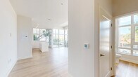 Located in the heart of San Diego, this contemporary two-story residence offers a bright, modern living experience across two well-proportioned floors. Light wood-tone flooring flows throughout both levels, complementing the crisp white walls and creating a clean, cohesive aesthetic.

The lower floor serves as the main living and kitchen area. Floor-to-ceiling glass windows and sliding doors bathe the open living space in natural light and provide direct access to an outdoor balcony with views of the surrounding neighborhood. The kitchen is thoughtfully designed with white shaker cabinetry, dark countertops, a classic white subway tile backsplash, and a striking marble-topped island. Stainless steel appliances, including a gas range, built-in microwave, refrigerator, and dishwasher, complete the space.

A sculptural staircase with sleek black metal railings connects the floors, acting as a design focal point. The upper floor offers generous open living space, also bathed in natural light from large windows overlooking the streetscape. This level includes a well-appointed bathroom with a tiled tub-shower combination, a white vanity, and wood-look flooring. A spacious walk-in closet with built-in shelving provides ample storage. A hallway connects the upper-level rooms, lending the layout a practical, organized flow throughout.