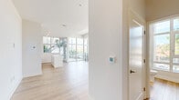 Located in the heart of San Diego, this contemporary two-story residence offers a bright, modern living experience across two well-proportioned floors. Light wood-tone flooring flows throughout both levels, complementing the crisp white walls and creating a clean, cohesive aesthetic.

The lower floor serves as the main living and kitchen area. Floor-to-ceiling glass windows and sliding doors bathe the open living space in natural light and provide direct access to an outdoor balcony with views of the surrounding neighborhood. The kitchen is thoughtfully designed with white shaker cabinetry, dark countertops, a classic white subway tile backsplash, and a striking marble-topped island. Stainless steel appliances, including a gas range, built-in microwave, refrigerator, and dishwasher, complete the space.

A sculptural staircase with sleek black metal railings connects the floors, acting as a design focal point. The upper floor offers generous open living space, also bathed in natural light from large windows overlooking the streetscape. This level includes a well-appointed bathroom with a tiled tub-shower combination, a white vanity, and wood-look flooring. A spacious walk-in closet with built-in shelving provides ample storage. A hallway connects the upper-level rooms, lending the layout a practical, organized flow throughout.
