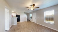 Located at 14100 Rio Bonito Rd in Houston, Texas, this two-story home offers a practical and well-appointed layout across two floors, with 3 bedrooms, 3 bathrooms, and a host of thoughtful finishes throughout. The main floor features an open living area with warm wood-look vinyl flooring, neutral gray walls, and a ceiling fan with light fixture. Natural light filters in through several windows, creating a bright and welcoming atmosphere. The kitchen is a standout feature, outfitted with white shaker-style cabinetry, granite-look countertops, black appliances including a refrigerator and electric range, and a convenient pass-through to a ground-floor bathroom. Upstairs, the three bedrooms are carpeted for comfort, with multiple windows offering outdoor views and ample natural light. The primary bedroom includes its own ceiling fan and generous closet space. The bathrooms are clean and functional, featuring white subway tile tub/shower combinations, wood-look tile flooring, white vanities with granite-style countertops, and brushed nickel fixtures. Additional spaces include a laundry area, a patio, hallway, and multiple closets. The home's neutral palette and consistent finishes give it a cohesive, move-in-ready feel throughout.