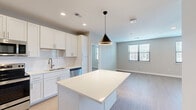Located at 2120 NW Lowenstein Dr in Lee's Summit, Missouri, this single-story residence showcases a clean, contemporary design with a cohesive neutral color palette throughout. The open-concept kitchen serves as a central highlight, featuring white shaker-style cabinetry extending to the ceiling, a classic subway tile backsplash, light quartz countertops, and a full suite of stainless steel appliances including a refrigerator with ice maker, range, microwave, and dishwasher. A center island with additional storage provides extra prep space and is accentuated by a modern pendant light above.

The kitchen flows naturally into a bright living area, which benefits from multiple windows with blinds allowing ample natural light. Sliding glass doors lead to an outdoor space, further enhancing the open feel. Light wood-look flooring runs consistently throughout the unit, lending warmth and visual continuity.

The bedrooms are generously proportioned, each featuring windows that invite natural light, neutral wall tones, and ceiling fans where applicable. The primary bathroom includes a glass-enclosed walk-in shower with brushed nickel fixtures and a white vanity with quartz countertop. A secondary bathroom offers a full tub-shower combination with matching brushed nickel hardware. The overall ambiance is fresh, bright, and move-in ready.