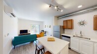 This well-appointed single-floor unit offers a thoughtfully designed open-concept layout that seamlessly connects the kitchen, dining, and living areas. The kitchen is equipped with stainless steel appliances, warm-toned wood upper cabinetry, crisp white lower cabinets, and a quartz-topped island with bar seating — ideal for casual dining or meal prep. An exposed metal ductwork detail adds an industrial-modern accent to the space. The living area is bright and welcoming, anchored by large sliding glass doors that open to a private balcony overlooking lush greenery, filling the room with natural light. A dedicated in-unit stacked washer and dryer adds everyday convenience. The two bedrooms are comfortably sized with plush carpeted floors, large windows, and generous closet space — one featuring a walk-in closet with direct access to the bathroom. The bathroom is clean and functional, featuring a white vanity with an undermount sink, a framed mirror, and wood-look flooring that ties the space together. Throughout the unit, light wood-look flooring in the main living areas and a neutral white palette create a bright, cohesive, and modern atmosphere.