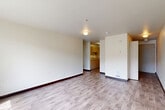Located on the third floor at 4730 21st Ave NE in Seattle's University District, this two-bedroom, one-bathroom unit offers a practical and well-organized layout across a single floor. The open living area features light-toned hardwood-style flooring, neutral walls, and a large window that fills the space with natural light and provides views of the surrounding neighborhood. The kitchen, visible from the living area, is equipped with warm wood cabinetry and a sink, offering a functional workspace. A hallway connects the main living spaces to the bedrooms and bathroom, with a utility closet housing the water heater tucked conveniently along the corridor. Both bedrooms are carpeted for comfort, with neutral tones and ample wall space. The primary bedroom includes a closet and a window overlooking mature trees, lending a serene, nature-connected feel. The second bedroom features a distinctive round window, adding a unique architectural touch. The full bathroom is finished with hardwood-style flooring and includes a full-size soaking tub with a shower. Throughout the unit, the clean, understated design palette creates a calm and move-in-ready atmosphere suited for everyday living.