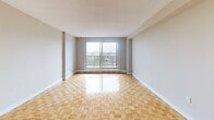 Located at 3000 Victoria Park Ave in Toronto's North York area, this well-appointed unit offers four bedrooms, two full bathrooms, and a functional single-floor layout. The living room is generously sized, featuring classic parquet flooring and a sliding glass door that opens onto a private balcony with open city views — an inviting space filled with natural light. The kitchen is a standout feature, outfitted with high-gloss white cabinetry, a subway tile backsplash, dark granite countertops, stainless steel appliances including a refrigerator and electric range, and large-format grey tile flooring. A peninsula provides added counter space and a natural divider between the kitchen and living areas. The four bedrooms are comfortably proportioned, each featuring warm parquet flooring and neutral wall tones. The primary bedroom benefits from large windows with expansive outdoor views. Both bathrooms are finished with white tile surrounds, soaker tubs with showers, and dark tile floors, maintaining a clean, functional aesthetic throughout. A dedicated closet adds practical storage. The overall ambiance is bright, clean, and functional — well-suited for a variety of living arrangements.