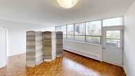 Located in the Hillsboro building in Toronto, Ontario, this thoughtfully laid-out one-bedroom, one-bathroom unit offers an efficient and comfortable living experience across a single floor. The bedroom is generously proportioned, featuring warm parquet hardwood flooring, two built-in closets with ample hanging space, and a wall of floor-to-ceiling windows that frame impressive panoramic views of the Toronto skyline — flooding the room with natural light. The kitchen is functional and well-appointed, with dark granite-style countertops, a tile backsplash, white cabinetry extending to the ceiling for maximized storage, and stainless steel appliances including an electric range and over-the-range microwave. The bathroom presents a clean, modern aesthetic with white subway tile extending from floor to ceiling, a dark stone vanity countertop, white cabinetry with chrome hardware, and a large mirror that enhances the sense of space. Two hallways connect the rooms, providing a practical flow throughout the unit. The parquet hardwood flooring visible in the main living areas adds warmth and character, complementing the bright, white walls and creating an inviting overall ambiance ideal for urban living.