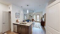 Located at 141 Foremost Dr in Austin, TX 78745, this one-bedroom, one-bathroom residence offers a thoughtfully designed single-floor layout that maximizes every square foot. The open-concept kitchen and living area serves as the heart of the home, where dark espresso cabinetry, granite countertops, a double stainless steel sink, and stainless steel appliances — including a range, microwave, and dishwasher — create a functional and stylish kitchen. Pendant lighting above the island adds a modern touch. The kitchen flows seamlessly into the living room, which is bathed in natural light from a set of French doors that open to outdoor views and feature a ceiling fan overhead. Light wood-style flooring runs throughout the main living areas, contributing to a warm, cohesive aesthetic. The bedroom offers carpeted flooring, a ceiling fan, a dedicated closet with double doors and built-in hanging rods, and a window with natural light. The bathroom is well-equipped with dark cabinetry, granite countertops, a large framed mirror, and wood-look tile flooring. Throughout the space, clean white walls and modern finishes create a bright, contemporary atmosphere well-suited for Austin living.