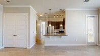 Located at 26493 E University Dr in Little Elm, TX, this one-bedroom, one-bathroom residence offers a well-designed single-floor layout that maximizes functionality. The open-concept living, dining, and kitchen area serves as the heart of the home, finished with light wood-look tile flooring and crown molding throughout. The kitchen is outfitted with dark espresso cabinetry, granite countertops, a breakfast bar peninsula, stainless steel appliances including a refrigerator, range, and microwave, plus a tiled backsplash and a pantry for added storage. Large windows in the dining area flood the space with natural light and offer views of the surrounding neighborhood. The spacious bedroom includes access to a dedicated walk-in closet with built-in shelving and hanging rods. The bathroom features granite countertops with dark cabinetry and a soaking tub with a tiled shower surround. Additional conveniences include an in-unit laundry area and a private patio accessible from the living space. Crown molding, track lighting, and a neutral color palette lend a clean, polished feel throughout the entire unit.