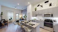 Located at 6314 Naaman Forest Blvd in Garland, TX, this well-designed 2-bedroom, 2-bathroom residence offers a thoughtful single-level layout with modern finishes throughout. The open-concept kitchen and living area serves as the heart of the home, highlighted by soaring ceilings, a dramatic textured accent wall, and large windows that invite natural light. The kitchen features gray cabinetry, stainless steel appliances, subway tile backsplash, and a generous granite-topped island with bar seating — ideal for both cooking and entertaining. Wood-look flooring flows seamlessly through the main living areas, adding warmth and continuity. The primary bedroom offers a comfortable retreat with plush carpet, a bold geometric accent wall, and access to a well-organized walk-in closet with built-in shelving and hanging rods. The en-suite bathroom includes granite countertops and light wood-tone flooring. The second bedroom is equally inviting, with soft carpet and warm ambient lighting. A second full bathroom features a tub-shower combination and light, airy finishes. Both closets provide ample storage with multi-tiered shelving systems. The overall ambiance is contemporary and cohesive, blending clean lines with stylish design details throughout.