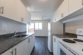 Located at 55 McMurchy Ave N in Brampton, Ontario, this one-bedroom, one-bathroom unit offers a practical and well-organized layout across a single floor. The open-concept living, dining, and kitchen area forms the heart of the unit, providing a cohesive and functional living space. Large sliding glass doors and generously sized windows flood the living and dining area with natural light while offering open views of the surrounding neighbourhood. The laminate hardwood-style flooring runs consistently throughout, lending a clean and cohesive aesthetic to every room. The galley-style kitchen is efficiently designed, featuring white cabinetry with brushed gold hardware, dark granite-look countertops, a stainless steel sink, a white refrigerator, and an electric stove, with a tile backsplash completing the look. The bedroom is a comfortable, well-proportioned room with a dedicated window that brings in natural light and neighbourhood views, complemented by baseboard heating. The bathroom is finished with white subway tile surrounding a full soaker tub and shower combo, along with a window for ventilation. Throughout the unit, neutral warm-white walls and clean finishes create a bright, move-in-ready atmosphere.