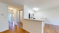 Located on Burbank Boulevard in the Van Nuys neighborhood of Los Angeles, this 2-bedroom, 2-bathroom residence offers a well-organized single-floor layout. The combined kitchen and living area forms the heart of the home, featuring a peninsula-style kitchen with light stone countertops, stainless steel appliances including a refrigerator, range, and microwave, white cabinetry, and a double-basin sink with a brushed nickel faucet. Warm hardwood-style flooring flows consistently throughout the entire unit, contributing to a cohesive and inviting aesthetic.

The primary bedroom is generously sized and is bathed in natural light through a large picture window framing views of mature trees. It includes a mirrored sliding-door closet that adds depth and storage. The second bedroom also features wood-style flooring, natural light, and an exterior-facing window. Both rooms are finished with clean white walls that complement the bright, neutral palette of the home.

The two bathrooms are functionally appointed; one features a tub-shower combination enclosed by sliding frosted glass doors with chrome fixtures. The clean, understated design throughout the unit creates a practical and comfortable living environment suited for everyday Los Angeles living.