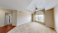 Located along South Lake Houston Parkway in Houston, TX, this two-bedroom, two-bathroom single-floor residence offers a thoughtfully laid-out floor plan with a warm, neutral color palette throughout. The spacious living area flows into a combined dining room and kitchen, creating an open, functional hub for daily living. The kitchen is outfitted with rich cherry-toned cabinetry, granite-style countertops, a tile backsplash, and a full suite of black appliances including a refrigerator, range, dishwasher, and microwave. Wood-look flooring adds warmth to the kitchen and dining area.

The primary bedroom is generously sized, highlighted by a distinctive tray ceiling, crown molding, a ceiling fan, and a striking arched window that floods the space with natural light. It connects to a private bathroom featuring a wood-toned vanity and access to a walk-in closet with built-in shelving. The second bedroom is equally well-appointed with plush carpeting, a ceiling fan, and large windows offering outdoor views. Both bedrooms share a comfortable, carpeted feel. Additional features include a hallway, two closets, and a dedicated laundry area, rounding out this practical and inviting residence.