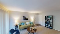 This single-floor residence on Madison Avenue in Indianapolis offers a comfortable and functional layout designed for everyday living. The living room serves as the heart of the home, featuring soft carpeted flooring, neutral gray walls, and a large sliding glass door that floods the space with natural light and provides direct views of the outdoors. The open, airy feel is enhanced by smooth ceilings throughout.

The dining area is situated adjacent to the living space and features warm hardwood-style flooring, a ceiling fan with light fixture, and a window overlooking an outdoor patio area, allowing for natural light and ventilation. The kitchen is outfitted with crisp white cabinetry, dark countertops, a double sink, and black appliances including a refrigerator and dishwasher, all set on durable hardwood-style flooring.

The bedroom is a restful retreat with plush carpeting, a generous window that brings in ample natural light, and sufficient space for a full bedroom suite. The bathroom connects via a hallway with hardwood-style flooring and features a white vanity with built-in storage, a mirror, and clean, neutral finishes. Throughout the residence, a consistent neutral color palette and thoughtful layout create a cohesive and inviting living environment.