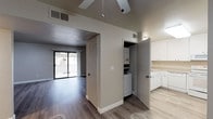 This single-floor unit offers a well-organized layout designed for comfortable everyday living. The living room serves as a central gathering space, finished with wood-style laminate flooring and anchored by a tiled fireplace. A sliding glass door provides direct access to an outdoor patio and fills the room with natural light, while a ceiling fan adds practical comfort overhead.

The kitchen is efficiently arranged in an L-shaped configuration, outfitted with white cabinetry, speckled laminate countertops, and a full suite of white appliances including a dishwasher, range, and built-in microwave. The adjacent hallway conceals a dedicated laundry closet housing a stacked washer and dryer unit, keeping essentials conveniently accessible.

Two bedrooms are each carpeted and include closets, with windows that bring in natural light. One bedroom features a standard sliding closet door, while the other includes an open reach-in closet. Both bathrooms are finished with wood-style flooring, white vanity cabinetry, and a tub-shower combination. The neutral color palette of warm gray and white tones is maintained consistently throughout the unit, lending a clean and cohesive aesthetic across all spaces.