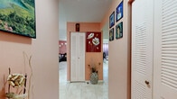 Located at 3300 El Jardin Dr in Hollywood, Florida, this one-bedroom, one-bathroom residence offers a practical and well-organized single-floor layout. Light-toned ceramic tile flooring runs consistently throughout the space, contributing to a clean and cohesive look. The hallways feature warm salmon-pink accent walls and louvered closet doors, providing useful built-in storage as you move through the home.

The living room is a comfortable gathering space with a textured ceiling, a window allowing natural light, and enough room to accommodate a large sectional sofa and entertainment setup. Adjacent to the living area, the kitchen is well-appointed with white cabinetry extending to the ceiling, a yellow tile backsplash, a U-shaped counter layout, and a window above the sink. The kitchen offers ample counter and storage space to support everyday cooking needs.

The bedroom is a generously sized retreat featuring light blue walls, a textured ceiling, a large built-in closet with louvered doors, and a window dressed with purple curtains that filter natural light. White dresser storage and wall-mounted shelving add to its functionality.

The bathroom includes a single-sink vanity with under-cabinet storage, a toilet, and a tub-shower combination. The tile flooring continues here, maintaining a uniform aesthetic. Two hallways connect the rooms efficiently, completing this compact yet well-structured home.
