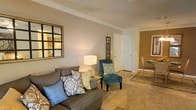Located at 8160 County Road 64 in Daphne, Alabama, this single-floor residence offers a welcoming and comfortable living environment with thoughtfully designed interiors. The living area serves as the heart of the home, showcasing warm neutral wall tones, plush carpeting, and elegant crown molding that adds a refined architectural touch throughout. Natural light filters into the space, enhancing the bright and airy ambiance. The living room is generously proportioned, providing ample room for seating arrangements, and flows naturally into adjacent areas of the home. A decorative wall mirror and tasteful accents contribute to the room's warm, layered aesthetic. The transition to the dining area is seamless, with an open layout that encourages easy movement between spaces. Interior doors feature classic paneled designs that complement the traditional styling of the home. The overall atmosphere is cozy yet polished, making it well-suited for both everyday living and entertaining. The neutral color palette throughout the interior allows for versatile décor choices, while the crown molding and carpeted floors add character and comfort. This single-story layout offers convenience and accessibility, making it a practical and appealing option in the Daphne, Alabama community.