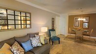 Located at 8160 County Road 64 in Daphne, Alabama, this single-floor residence offers a welcoming and comfortable living environment with thoughtfully designed interiors. The living area serves as the heart of the home, showcasing warm neutral wall tones, plush carpeting, and elegant crown molding that adds a refined architectural touch throughout. Natural light filters into the space, enhancing the bright and airy ambiance. The living room is generously proportioned, providing ample room for seating arrangements, and flows naturally into adjacent areas of the home. A decorative wall mirror and tasteful accents contribute to the room's warm, layered aesthetic. The transition to the dining area is seamless, with an open layout that encourages easy movement between spaces. Interior doors feature classic paneled designs that complement the traditional styling of the home. The overall atmosphere is cozy yet polished, making it well-suited for both everyday living and entertaining. The neutral color palette throughout the interior allows for versatile décor choices, while the crown molding and carpeted floors add character and comfort. This single-story layout offers convenience and accessibility, making it a practical and appealing option in the Daphne, Alabama community.