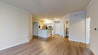 Located in Temple Terrace, FL, this 2-bedroom, 2-bathroom residence offers a thoughtfully designed single-floor layout with a warm, neutral color palette and wood-style flooring throughout. The combined kitchen and living area serves as the heart of the home, featuring crown molding, a peninsula with granite countertops, white cabinetry, and stainless steel appliances including a refrigerator, range, and microwave. The open layout connects seamlessly to the living room, which is accented by crown molding and a smart thermostat. Both bedrooms are generously proportioned, each offering ceiling fans, natural light from multiple windows with blinds, and views of surrounding greenery. The spacious primary bedroom is a standout, offering ample room and access to its own bathroom complete with a walk-in glass-door shower, granite vanity, and wood-style flooring. The second bathroom features a full tub-shower combination with tile surround. Three closets provide abundant storage throughout. A dedicated laundry room houses a full-size washer and dryer alongside the electrical panel. The overall ambiance is clean, bright, and move-in ready, blending functional design with modern finishes.