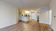 Located in Temple Terrace, FL, this 2-bedroom, 2-bathroom residence offers a thoughtfully designed single-floor layout with a warm, neutral color palette and wood-style flooring throughout. The combined kitchen and living area serves as the heart of the home, featuring crown molding, a peninsula with granite countertops, white cabinetry, and stainless steel appliances including a refrigerator, range, and microwave. The open layout connects seamlessly to the living room, which is accented by crown molding and a smart thermostat. Both bedrooms are generously proportioned, each offering ceiling fans, natural light from multiple windows with blinds, and views of surrounding greenery. The spacious primary bedroom is a standout, offering ample room and access to its own bathroom complete with a walk-in glass-door shower, granite vanity, and wood-style flooring. The second bathroom features a full tub-shower combination with tile surround. Three closets provide abundant storage throughout. A dedicated laundry room houses a full-size washer and dryer alongside the electrical panel. The overall ambiance is clean, bright, and move-in ready, blending functional design with modern finishes.