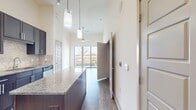 This contemporary 560 square foot apartment at The Flats at Palisades offers a well-designed one-bedroom layout. The open-concept living area seamlessly integrates with the kitchen, featuring dark wood cabinetry, stainless steel appliances, and a central island. The kitchen's sleek design is complemented by pendant lighting and track lights, creating a modern ambiance.

The living room and bedroom both boast large windows that flood the space with natural light and provide scenic views of the surrounding landscape. Sliding glass doors in both rooms lead to a private balcony, perfect for outdoor relaxation.

The bathroom showcases a spacious design with a separate bathtub and shower area, complemented by warm-toned tile flooring. A generously sized walk-in closet offers ample storage space, featuring built-in shelving and hanging rods.

The apartment includes an in-unit laundry area with full-sized washer and dryer, adding convenience to daily living. Throughout the space, neutral-toned walls and a mix of carpeted and wood-look flooring create a cohesive and inviting atmosphere. The thoughtful layout maximizes the use of space, making this compact apartment feel open and airy.