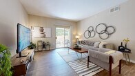 Located at 9001 Renner Blvd in Lenexa, Kansas, this single-floor, 2-bedroom, 2-bathroom home offers a thoughtfully designed layout with a warm, neutral palette throughout. The living room is a welcoming centerpiece, featuring wood-style flooring and a sliding glass door that fills the space with natural light and provides direct access to an outdoor patio. The galley-style kitchen is efficiently organized with light wood cabinetry, dark granite-style countertops, and stainless steel appliances including a refrigerator, range, and microwave. Adjacent to the kitchen, the dining area accommodates a full-sized dining table beneath pendant lighting, making it ideal for everyday meals or entertaining. Both bedrooms are carpeted and generously sized, each equipped with a ceiling fan and windows that allow ample natural light. The spacious primary bedroom offers a comfortable retreat with room for a full bedroom suite. The two bathrooms each feature a tub-shower combination with glass sliding doors, wood-style flooring, and warm-toned vanity cabinetry. Additional highlights include two closets, two hallways, and a dedicated laundry area, rounding out a practical and comfortable single-level home.