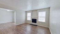 This two-story home offers a practical and efficiently designed layout, with living spaces on the ground floor and bedrooms distributed across both levels. The main floor features a living room highlighted by a wood-burning fireplace flanked by two windows that allow natural light to fill the space. Wood-look flooring runs throughout the main living areas, lending a clean, cohesive appearance. The galley-style kitchen is equipped with gray cabinetry, light stone-pattern countertops, a stainless steel sink, and a full-size refrigerator, making efficient use of the available space.

The three bedrooms include a primary bedroom featuring its own en-suite bathroom and a walk-in closet. The secondary bedrooms are carpeted and receive natural light through windows with blinds. All three bathrooms are consistently appointed with gray vanity cabinetry, granite-style countertops, large mirrors, and wood or wood-look flooring. Hallways on both floors provide connectivity between rooms, with staircases linking the two levels. The textured ceilings and neutral wall tones throughout contribute to the home's understated, move-in-ready aesthetic.