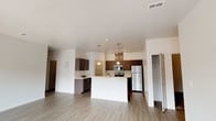 This single-floor residence offers a thoughtfully designed open-concept layout that seamlessly connects the living and kitchen areas. The spacious living room is bathed in natural light, courtesy of large windows that overlook the surrounding exterior, and features light-toned hardwood-style flooring that extends throughout the common areas. A set of sliding glass doors provides additional access to the outdoors, enhancing the bright, airy atmosphere.

The kitchen serves as a functional centerpiece, equipped with stainless steel appliances including a refrigerator, electric range, and microwave. Rich, dark cabinetry pairs with light countertops to create a modern contrast, while pendant lighting above the kitchen island adds a stylish touch. A dedicated pantry offers generous storage just steps from the cooking area.

The bedrooms are carpeted for comfort and include windows that allow natural light to filter in. The primary bathroom features a dual-sink vanity with a white countertop, dark cabinetry, a large mirror with vanity lighting, and access to a walk-in closet. A second bathroom offers a clean, efficient layout with a tub-shower combination, single-sink vanity, and matching contemporary finishes. Textured accent walls in select areas add subtle architectural character throughout the residence.