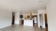 This single-floor residence offers a thoughtfully designed open-concept layout that seamlessly connects the living and kitchen areas. The spacious living room is bathed in natural light, courtesy of large windows that overlook the surrounding exterior, and features light-toned hardwood-style flooring that extends throughout the common areas. A set of sliding glass doors provides additional access to the outdoors, enhancing the bright, airy atmosphere.

The kitchen serves as a functional centerpiece, equipped with stainless steel appliances including a refrigerator, electric range, and microwave. Rich, dark cabinetry pairs with light countertops to create a modern contrast, while pendant lighting above the kitchen island adds a stylish touch. A dedicated pantry offers generous storage just steps from the cooking area.

The bedrooms are carpeted for comfort and include windows that allow natural light to filter in. The primary bathroom features a dual-sink vanity with a white countertop, dark cabinetry, a large mirror with vanity lighting, and access to a walk-in closet. A second bathroom offers a clean, efficient layout with a tub-shower combination, single-sink vanity, and matching contemporary finishes. Textured accent walls in select areas add subtle architectural character throughout the residence.