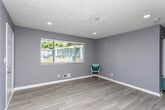 Located at 2001 Sylvan Rd SW in Atlanta, Georgia, this single-story home offers a thoughtfully updated interior with a clean, neutral color palette of cool grays and crisp white trim throughout. The open floor plan connects the living areas seamlessly, with light wood-look flooring extending through the main living spaces and kitchen, creating a cohesive and modern feel.

The kitchen is a standout feature, equipped with warm-toned wood cabinetry, granite countertops, a subway tile backsplash, and stainless steel appliances including a dishwasher, electric range, and microwave. Natural light filters in through a window, and a rear door provides convenient exterior access directly from the kitchen.

The bedrooms are carpeted for comfort and feature ceiling fans, natural light from windows with blinds, and ample wall space. The rooms maintain the home's consistent gray color scheme, lending a calm and unified atmosphere throughout.

A central hallway connects the living spaces to the bathroom, which includes a shower/tub combination with a decorative curtain and clean tile work. The hallway also houses an electrical panel and provides access to carpeted bedroom areas. Recessed lighting and textured ceilings are found in several rooms, adding to the home's updated character. Overall, the space presents a move-in ready interior with practical, modern updates.