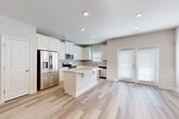 Located at 104 Cardinal George Ct in Easley, SC, this two-story home offers a thoughtfully designed layout with three bedrooms, four bathrooms, and an attached garage. The main level features light-toned hardwood-style flooring throughout, creating a bright and cohesive feel. The kitchen is a standout, showcasing white shaker cabinetry, granite countertops, a central island, tile backsplash, and a full suite of stainless steel appliances. A half bathroom on this floor provides added convenience. A wide hallway with recessed lighting connects the living areas and staircase seamlessly. The upper floor hosts all three bedrooms, each finished with plush carpeting. The spacious primary bedroom features a tray ceiling with crown molding and a ceiling fan, along with an en-suite bathroom and a generous walk-in closet with wire shelving. The additional bedrooms are well-proportioned with natural light from window treatments. Four bathrooms total ensure ample accommodation for residents and guests. The attached garage offers practical storage and parking. Throughout, neutral wall tones, recessed lighting, and clean architectural lines contribute to a modern, move-in-ready atmosphere.