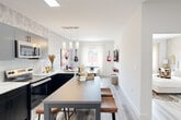 Located at 102 Washington Ave in Belleville, NJ, this thoughtfully designed single-floor unit offers a cohesive blend of modern aesthetics and functional living. The open-concept layout connects the kitchen and living area seamlessly, creating an inviting and efficient use of space. The kitchen is a standout feature, equipped with stainless steel appliances, sleek gray upper cabinetry, contrasting dark lower cabinets, and quartz countertops. A textured tile backsplash adds visual depth, while a center island with bar seating provides an ideal spot for casual dining or entertaining. Light wood-style flooring runs throughout, enhancing the bright, airy atmosphere. The living area extends naturally from the kitchen, bathed in natural light from large windows. The bedroom is a serene retreat, highlighted by a decorative accent wall with a bold geometric pattern, gold-toned drapery, and a built-in closet with ample storage. Natural light pours in through a generous window with outdoor views of the surrounding greenery. The bathroom is finished in a clean, contemporary style with a floating vanity, a sleek framed mirror, and cool gray tile flooring. Every detail in this space reflects a modern sensibility with high-quality finishes throughout.