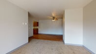 This single-floor unit offers a practical and comfortable layout across several well-defined living spaces. The open living and dining area features a combination of hardwood flooring and plush carpeting, creating a natural transition between zones. A ceiling fan with an integrated light fixture provides both ventilation and ambient lighting, while baseboard heating ensures year-round comfort. Built-in shelving adds functional storage to the living area.

The kitchen is efficiently arranged with warm-toned wood cabinetry, dark laminate countertops, and light hardwood flooring. White appliances, including a coil-burner electric range, refrigerator, and dishwasher, are all included. An overhead range hood completes the setup.

The bedrooms are carpeted and receive natural light through windows with outdoor views of surrounding trees. Baseboard heaters and wall-unit air conditioners are present, offering independent climate control. Neutral gray walls contribute to a calm, understated atmosphere throughout.

Two bathrooms serve the unit, each featuring wood-toned vanity cabinetry, a white countertop sink, a tub-shower combination, and light hardwood flooring. The dark-framed doors throughout the unit provide a subtle contrast to the light-colored walls, adding a cohesive design element across the space.