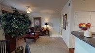 This single-floor residence offers a thoughtfully designed layout that balances comfort and functionality across multiple living areas. The living room serves as the heart of the home, featuring crown molding, soft carpeting, and generous natural light filtering through blinds and sheer curtains, creating a warm and inviting atmosphere. A dedicated dining area sits adjacent, benefiting from large windows and a glass door that brings in additional natural light.

The kitchen is well-equipped and efficiently arranged, featuring white cabinetry with ample storage, dark granite-style countertops, a peninsula breakfast bar, and a full suite of black appliances including a refrigerator, electric range, built-in microwave, and dishwasher. Track lighting overhead ensures the space is well-lit throughout.

Two spacious bedrooms each offer plush carpeting, ceiling light fixtures, and access to walk-in closets, providing generous storage. The neutral tones and clean lines of each bedroom contribute to a calm and restful environment.

Two full bathrooms serve the residence, each featuring dark countertops, white cabinetry, tub-shower combinations with tiled surrounds, and well-lit vanity mirrors. Wood-look flooring in the bathrooms adds a cohesive, modern touch. Overall, this residence presents a practical and comfortable living environment with consistent finishes throughout.