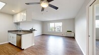 Located on Emelita Street in the Valley Village neighborhood of Los Angeles, this 1-bedroom, 2-bathroom unit offers a well-designed, functional layout across a single floor. The open-concept living and kitchen area is bright and welcoming, anchored by warm hardwood-style flooring and a ceiling fan overhead. A large window fills the living space with natural light while offering views of the surrounding neighborhood, including palm trees characteristic of the LA landscape. The kitchen is efficiently designed in a galley style, featuring white shaker cabinetry, dark countertops, stainless steel appliances including a gas range, microwave, and refrigerator, a skylight for added brightness, and a peninsula with a sink that opens to the living area. The bedroom is carpeted for comfort and includes a window overlooking the neighborhood, and connects to a dedicated walk-in closet outfitted with built-in shelving, hanging rods, and ample storage space. Two full bathrooms serve the unit, one of which includes a tub/shower combination with clean white finishes. The unit's neutral color palette, clean lines, and practical layout create a comfortable and modern living environment well-suited for everyday life in Los Angeles.